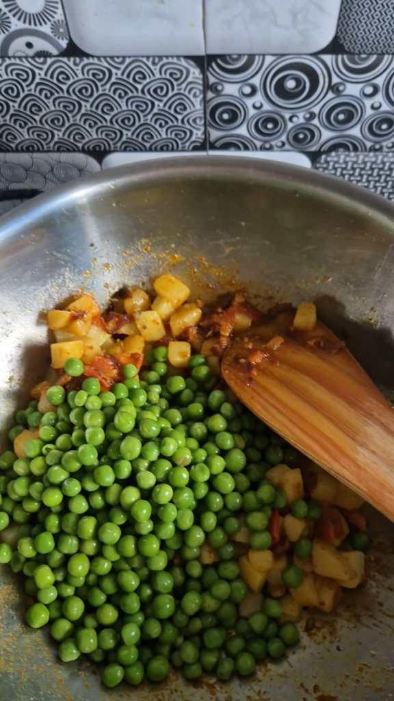 Adding in fresh peas to the curry