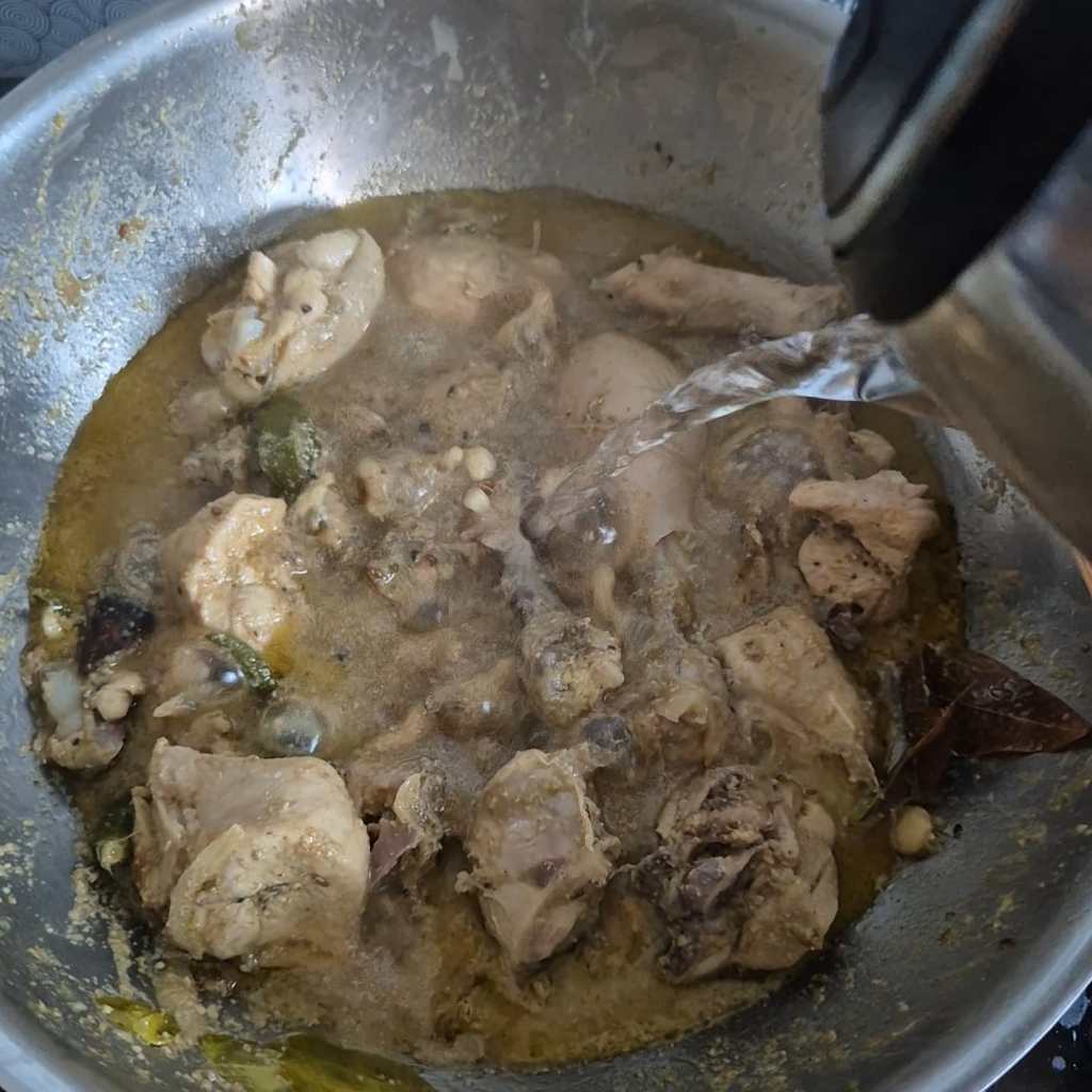 Adding hot water to a pan full of chicken curry